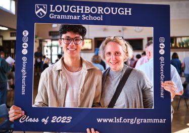 Pupil and parent pose with branded photo frame